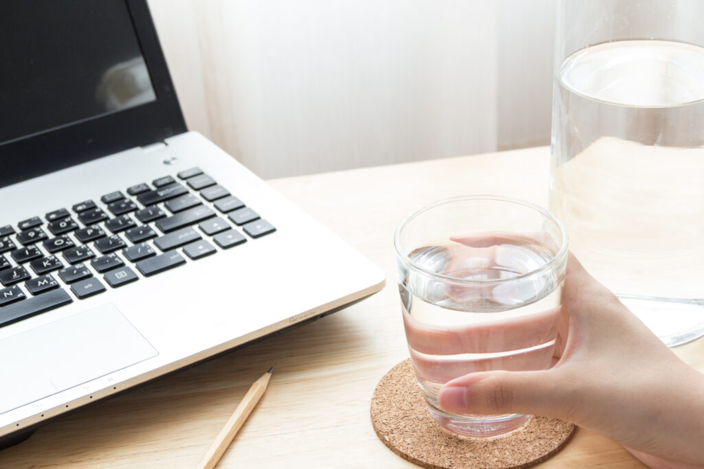 Hand Holding A Glass Of Water With Desk